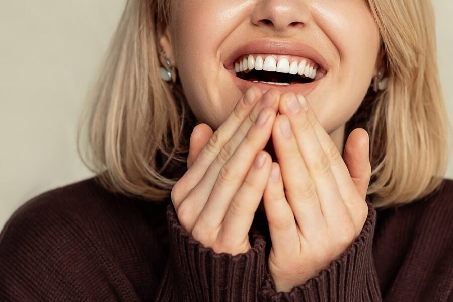 Close-up of a woman smiling with her hands held near her cheeks