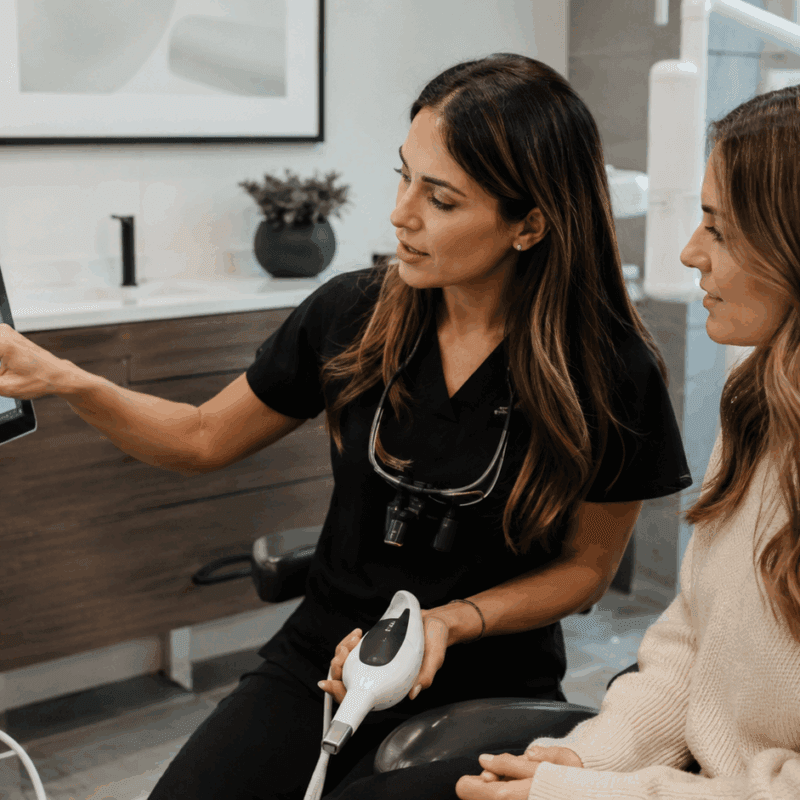 Dentist showing a patient a handheld dental instrument during a treatment consultation