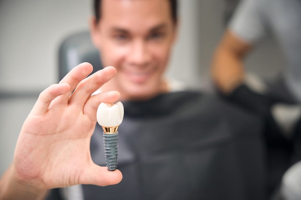 Client of aesthetic dentistry holding enlarged 3d model of dental implant