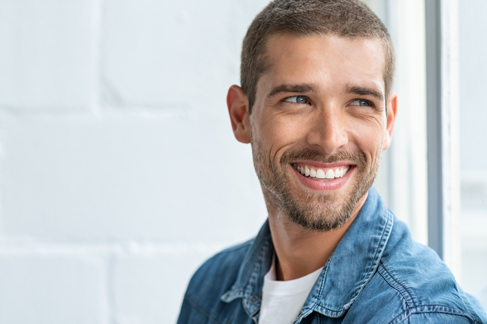 Smiling patient portrait Man with short hair and a beard smiling in a denim jacket