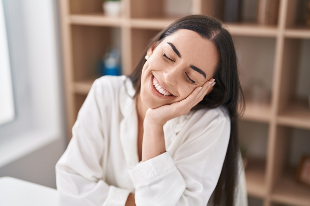 Relaxed, content smile Woman smiling with her eyes closed, resting her cheek in her hand