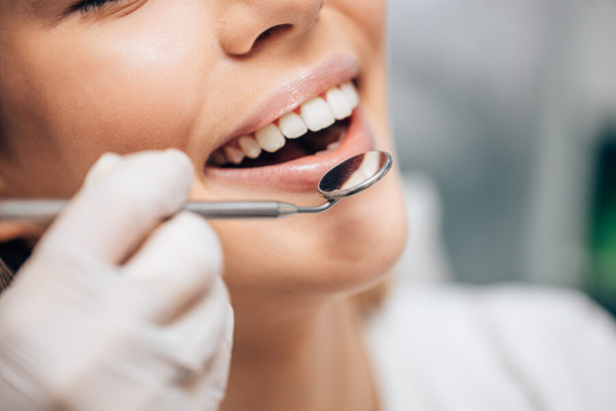Close-up of a gloved hand holding a dental mirror near a patient's open smile
