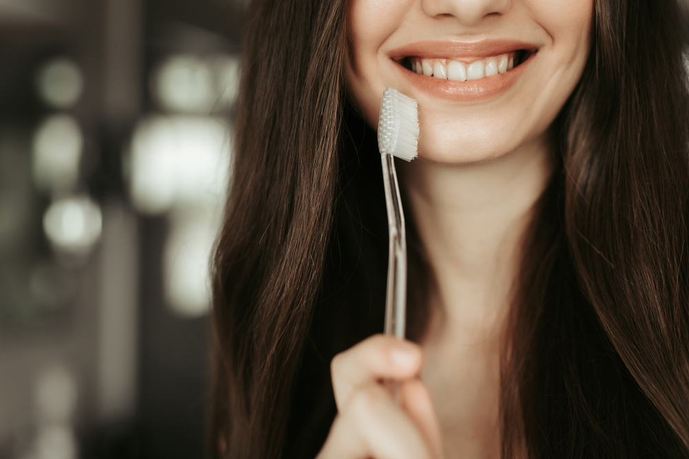 Daily dental implant care and oral hygiene Woman holding a toothbrush to demonstrate daily care for dental implants and natural teeth