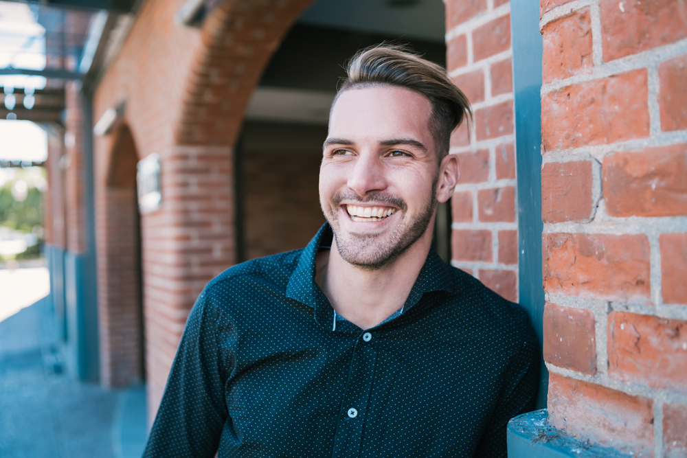 Confident smile after dental implant treatment Smiling man outdoors representing renewed confidence after replacing missing teeth with dental implants