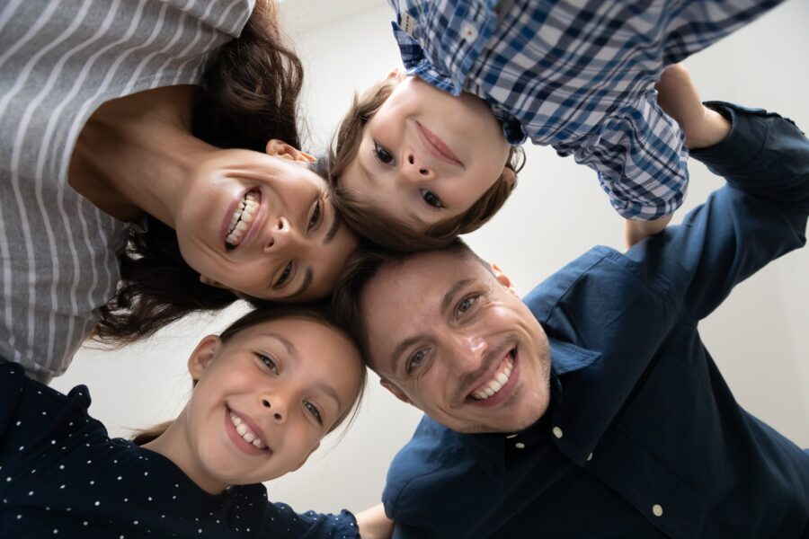 Family of four smiling with their heads together in a circle, viewed from below