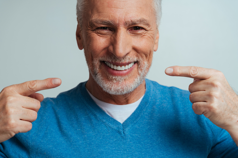 man smiling and showing their new dental implants | North County Aesthetics and Implants