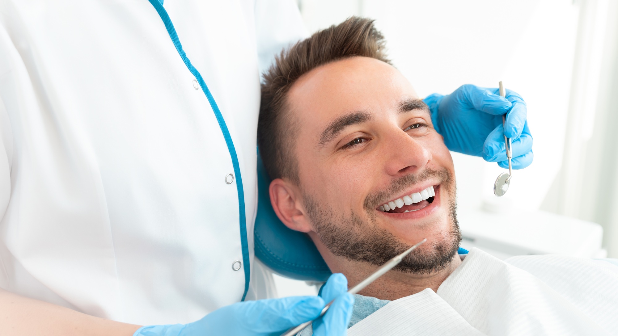 Dental implant evaluation and oral examination Dentist examining a smiling patient during an evaluation for dental implants in the San Marcos and San Diego community