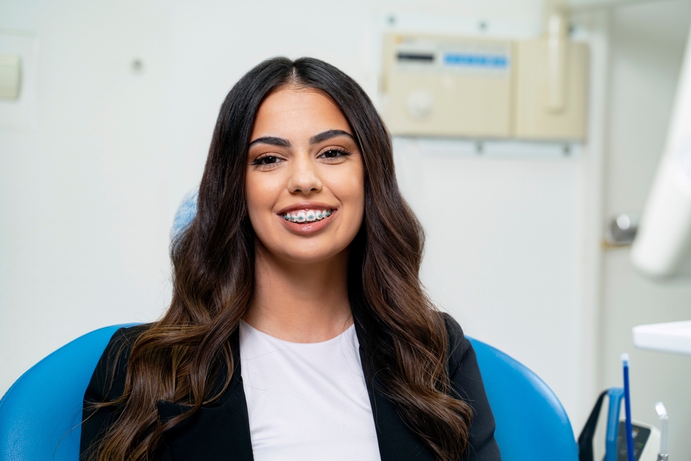 Smiling orthodontic patient wearing metal braces in a dental treatment room