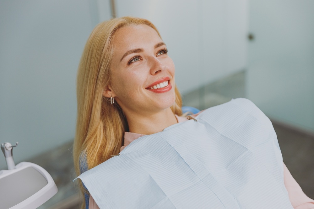 Smiling dental patient seated in a treatment chair during an All-on-X implant consultation in San Marcos