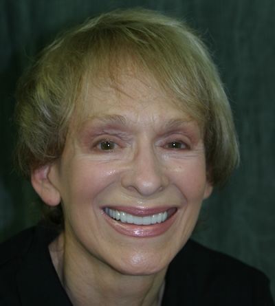 Customized veneers for an even, natural-looking smile Close-up portrait of a smiling woman displaying an even, bright smile after cosmetic dental treatment